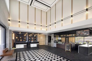 Een moderne lobby met een centraal zitgedeelte, een bar en een receptiebalie.