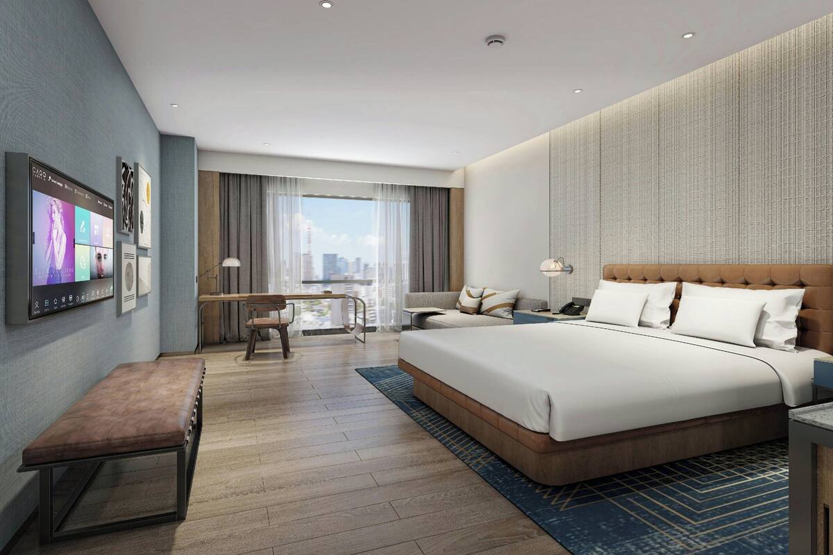 Een moderne hotelkamer met een groot bed, een bureau en een aan de muur bevestigde televisie.
