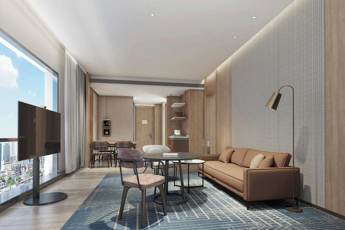 Een moderne hotelkamer met een groot raam, een bank, een eettafel en een televisie.