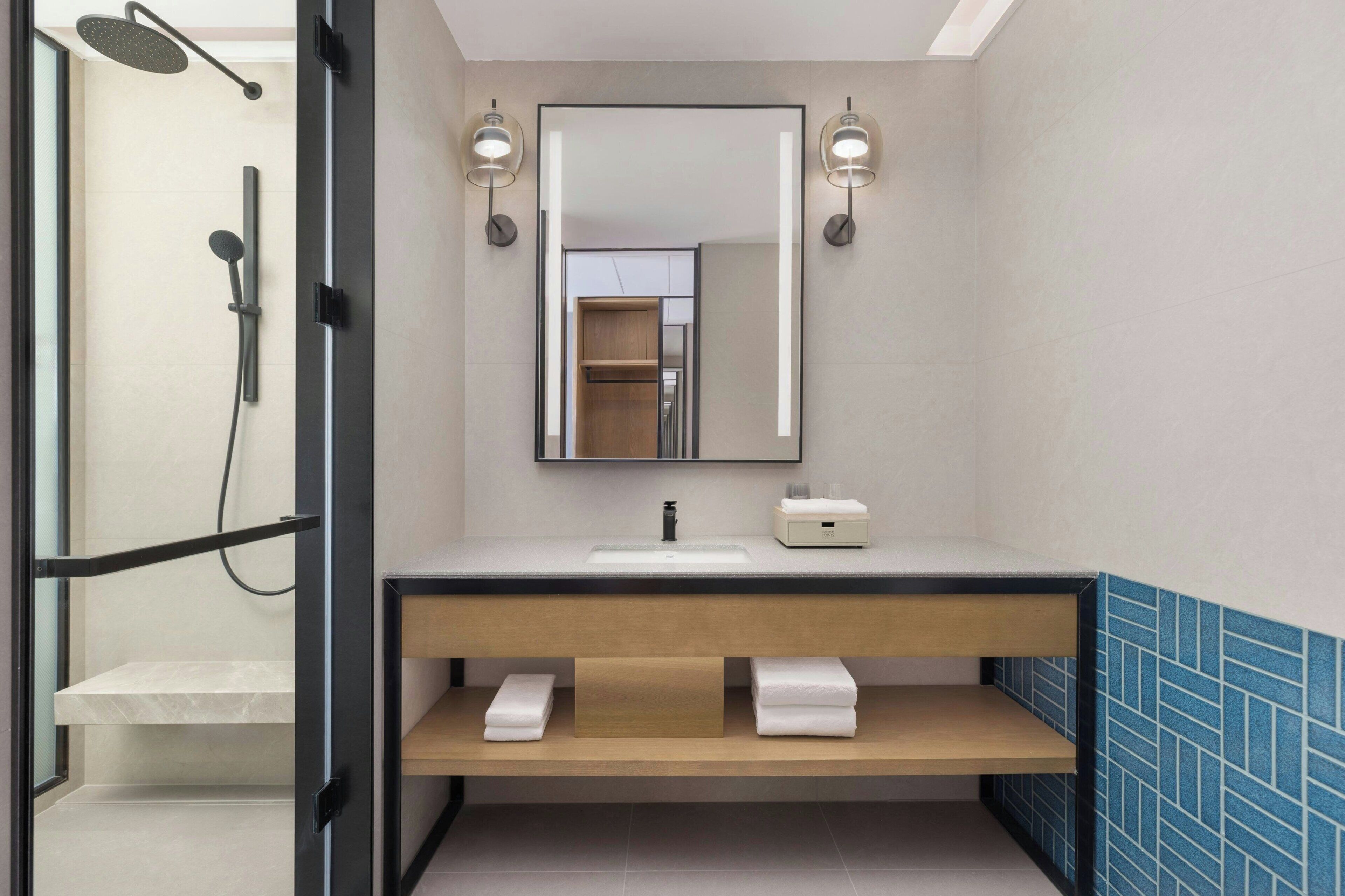 Ein modernes Badezimmer mit Dusche, Waschbecken, Spiegel und Handtuchhalter.