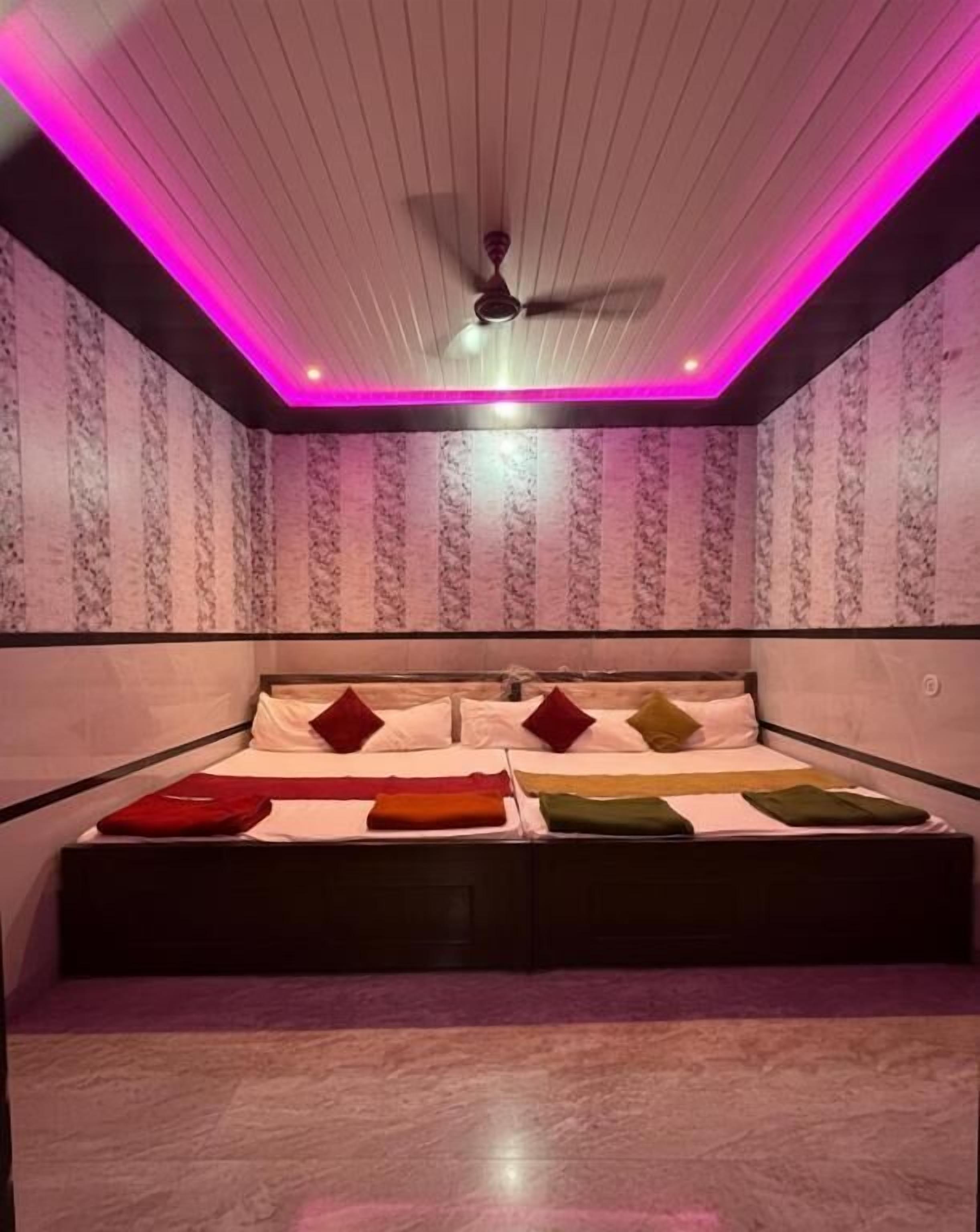 A room with a bed, ceiling fan, and patterned wallpaper.