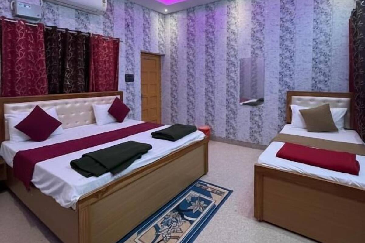 Een slaapkamer met twee bedden, een plafondventilator en een behang met een patroon.