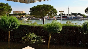 Vista sull'acqua con barche, un albero e un edificio sullo sfondo.