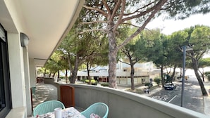 Un balcone con un tavolo apparecchiato per due, sedie e vista sulla strada e sugli edifici.