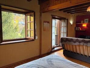 Ein Zimmer mit Bett, Fenster, Tür und einem Regal mit Büchern.