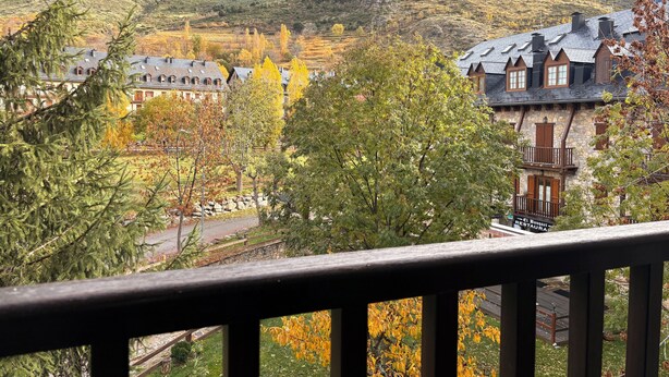 Eine gebirgige Landschaft mit traditioneller Architektur, ein Steinhaus mit einem Schild und Blick auf eine Straße.