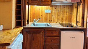 Eine kleine Küche mit Holzausstattung, einer integrierten Waschmaschine und einem kompakten Kühlschrank.