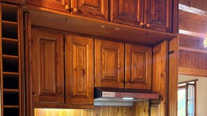 Eine kleine Küche mit Holzausstattung, einem Edelstahlspülbecken und einem integrierten Kühlschrank.