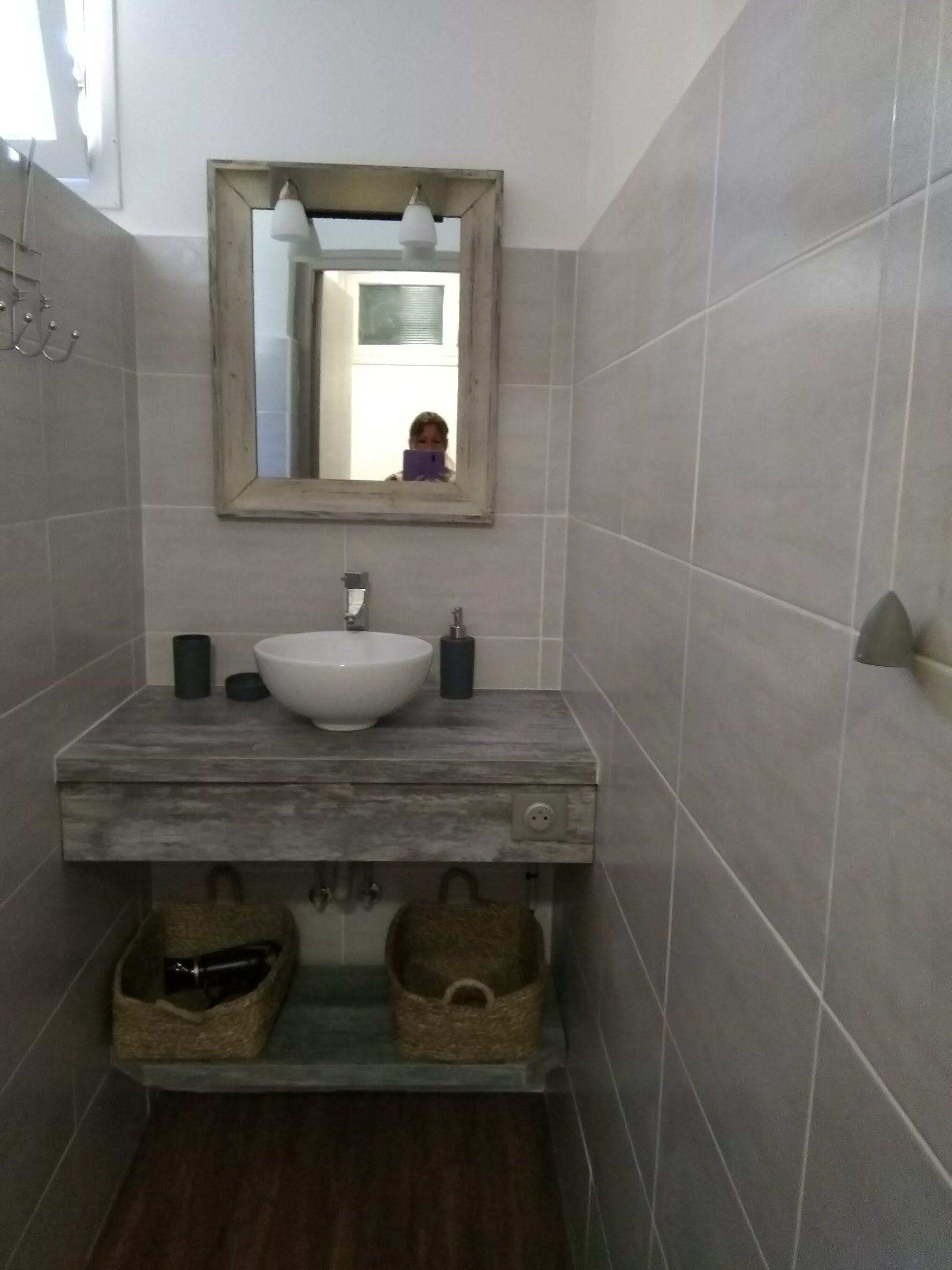 Un baño con un lavamanos blanco, un espejo y dos cestas debajo.