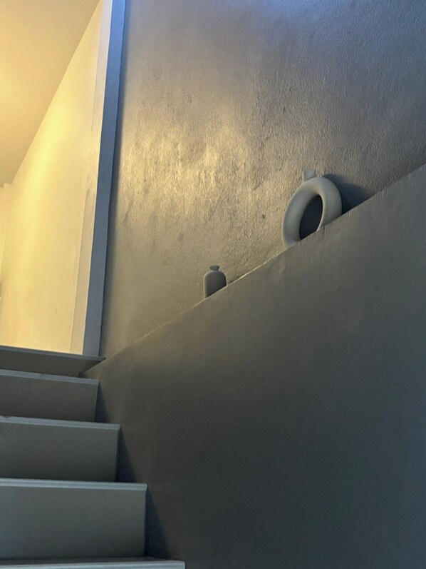 A staircase with a modern design, a textured wall, and a small, circular object on the wall. - Blissful well treat (Ko Pha-ngan)