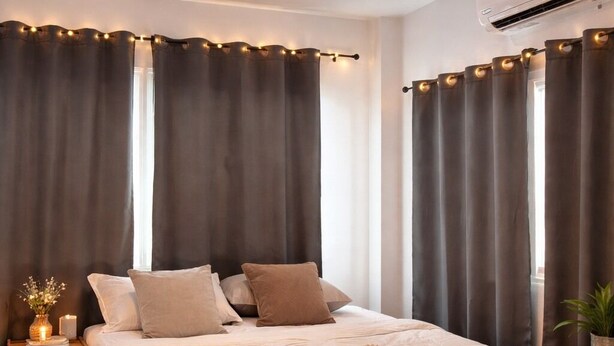 A bedroom with a bed, curtains, a nightstand, a bedside table, a plant, and an air conditioning unit. - Blissful well treat (Ko Pha-ngan)