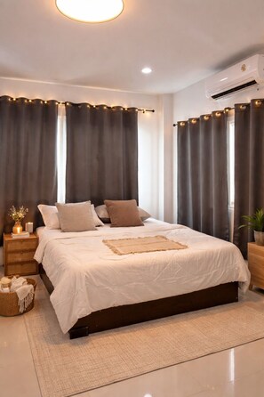 A bedroom with a bed, curtains, a nightstand, a bedside table, a plant, and an air conditioning unit. - Blissful well treat (Ko Pha-ngan)