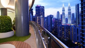A modern building with a curved facade, a rooftop garden, and a view of the Petronas Towers. - Luxury One Bedroom Apartment with KLCC View by JD Hospitality (Kuala Lumpur)