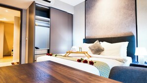 A hotel room with a bed, bedside table, and a wooden tray with towels and flowers. - Luxury One Bedroom Apartment with KLCC View by JD Hospitality (Kuala Lumpur)