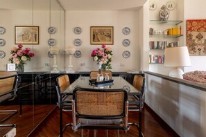 A dining area with a glass table, wicker chairs, and a vase of flowers. - Arno Dream by MMega Homes and Villas (Florence)