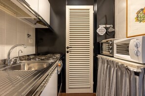 A compact kitchen with a stainless steel sink, a microwave, and a door with horizontal slats. - Arno Dream by MMega Homes and Villas (Florence)