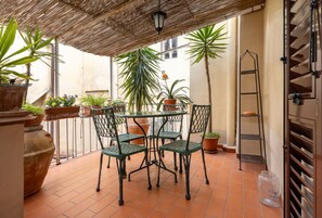 A patio with a table and chairs, surrounded by potted plants and a metal ladder. - Arno Dream by MMega Homes and Villas (Florence)