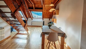 Een houten interieur met een eethoek, een trap en uitzicht op het omliggende landschap.