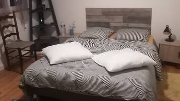 Une chambre à coucher comprenant un lit, une chaise en bois, une étagère avec des objets décoratifs et un tapis à motifs.