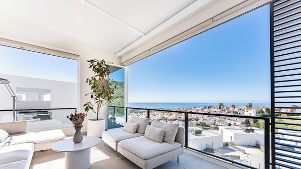 Ein Balkon mit einer Couch, einem kleinen Tisch und einem Topfpflanzen.
