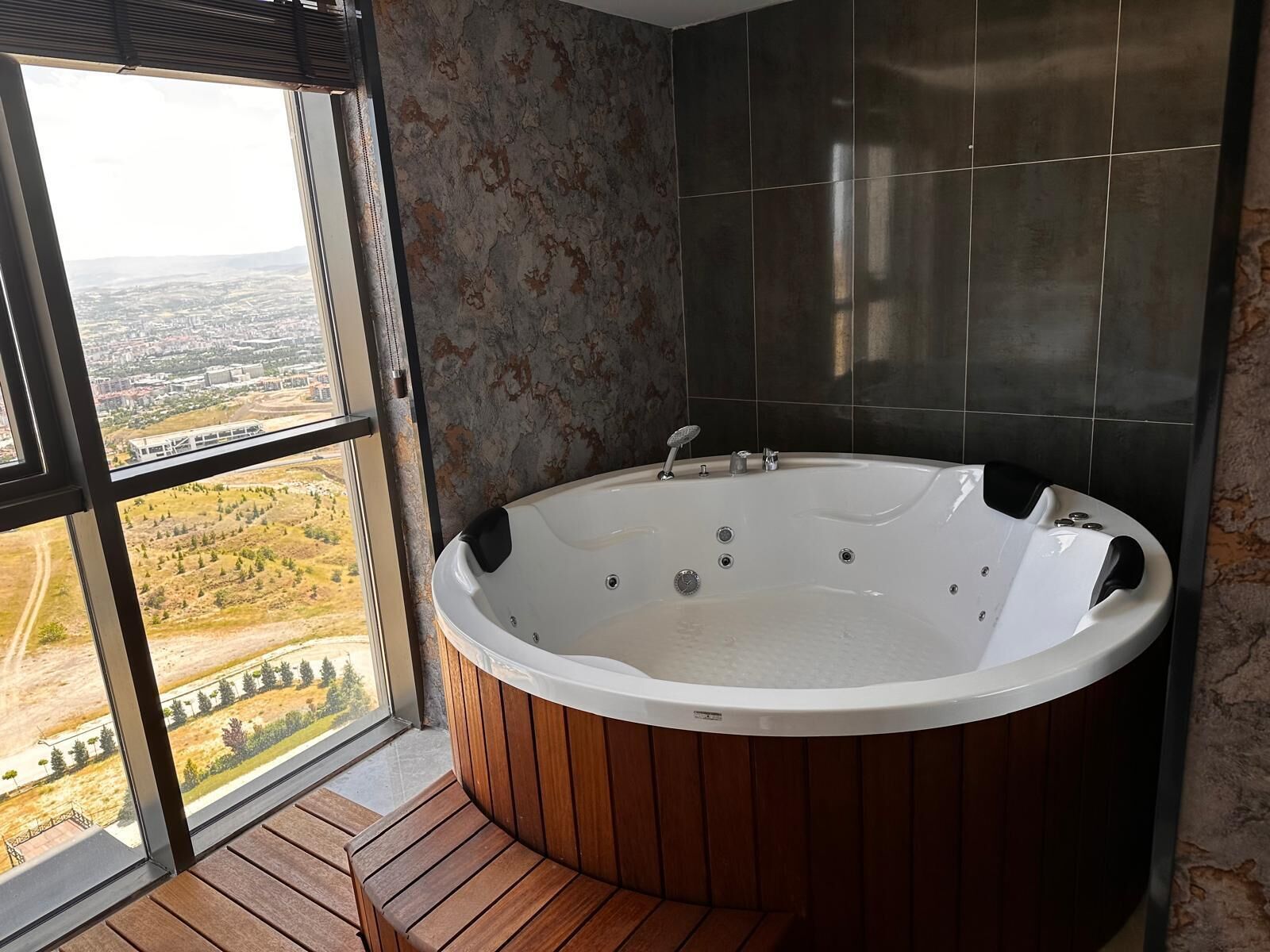A modern bathroom with a freestanding bathtub, large windows, and a view of the cityscape.