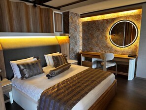 A modern bedroom with a bed, bedside table, desk, chair, and a round mirror. - WINDYHILL HOTEL (Elazig)