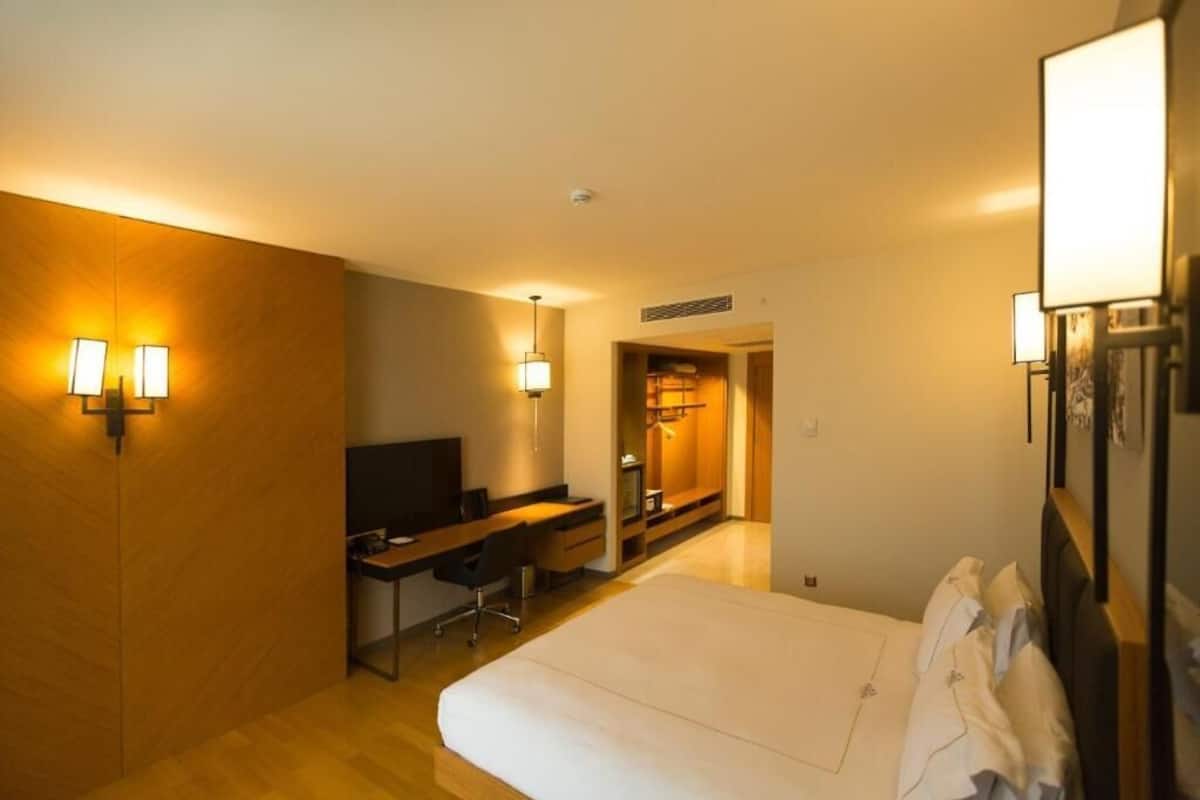 Ein Hotelzimmer mit Bett, Schreibtisch, Stuhl, Fernseher und Wandlampen.