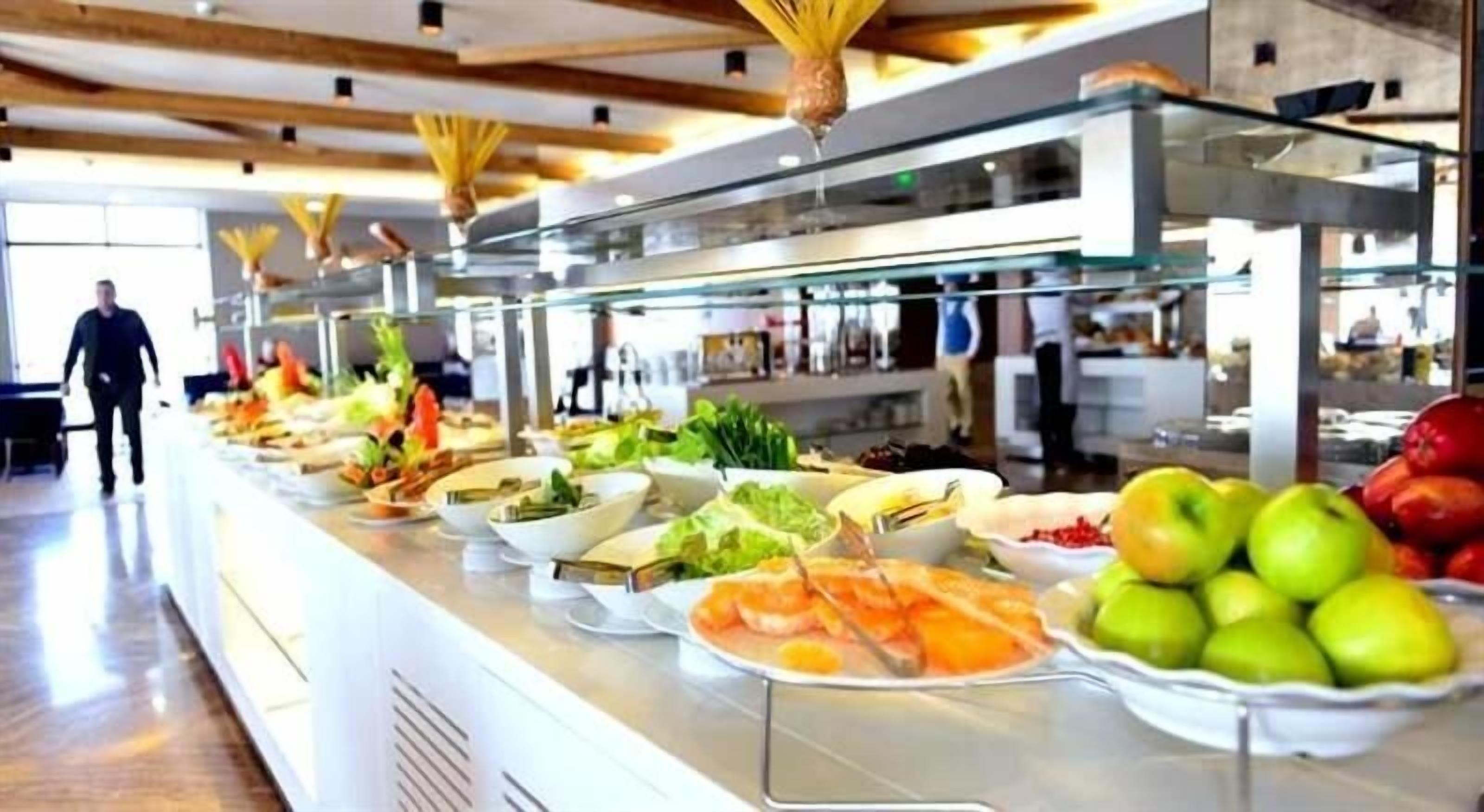 Un buffet proposant différents plats, et une personne qui se promène à l’arrière-plan.