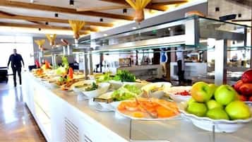 Un buffet proposant différents plats, et une personne qui se promène à l’arrière-plan.