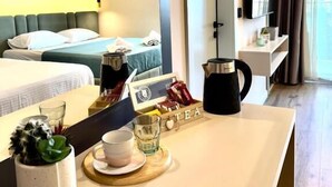 Et hotelværelse med en seng, et natbord med elkedel, en kop og en bakke med teposer.