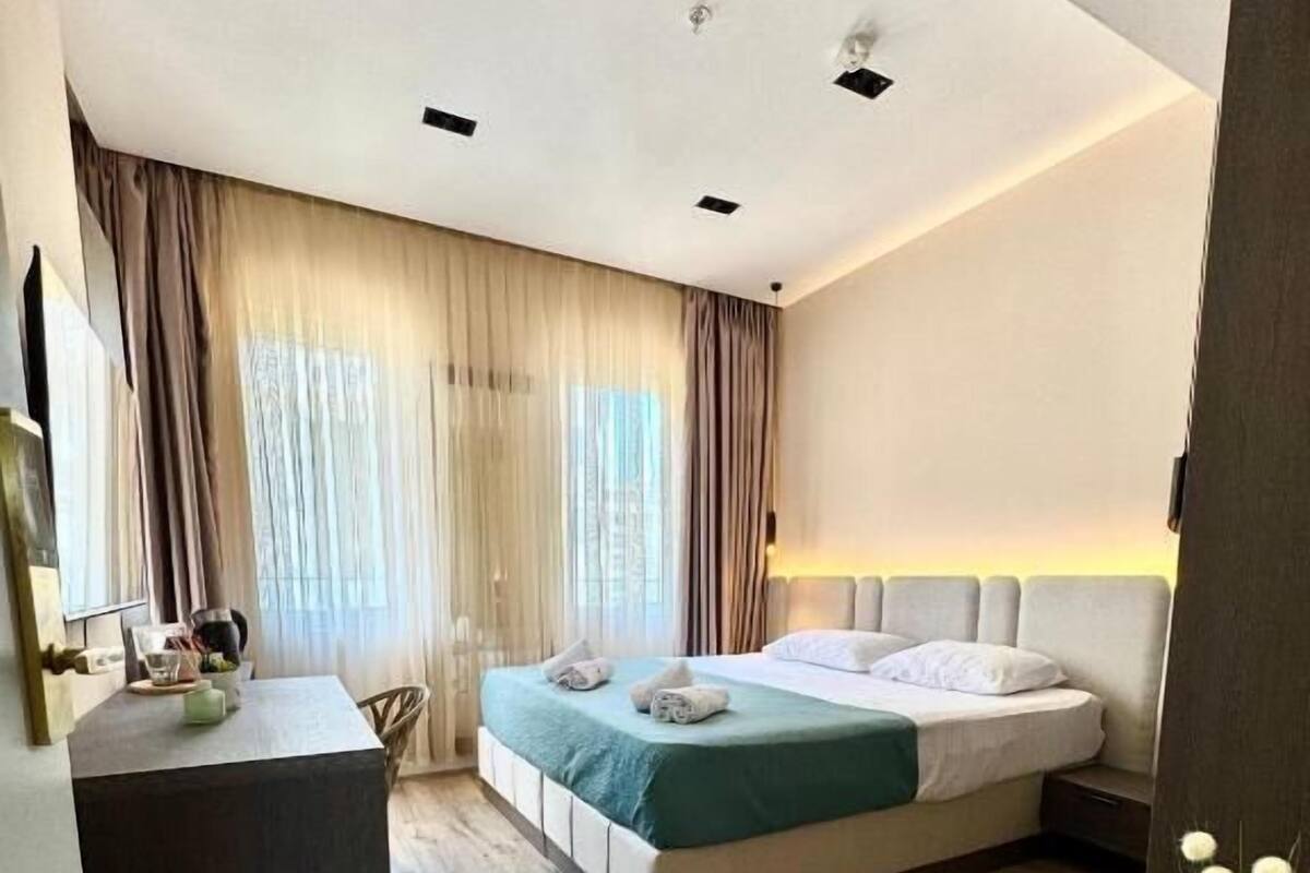 A modern hotel room with a bed, bedside table, and a small desk area.
