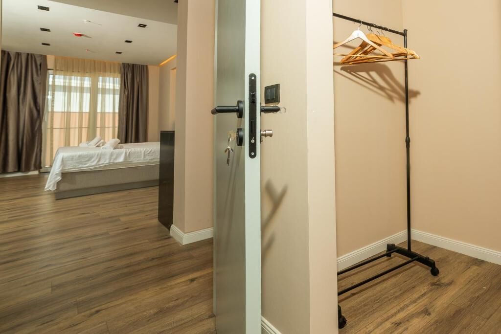 A hotel room with a bed, a wardrobe, and a door with a handle.