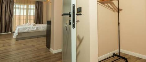 A hotel room with a bed, a wardrobe, and a door with a handle.