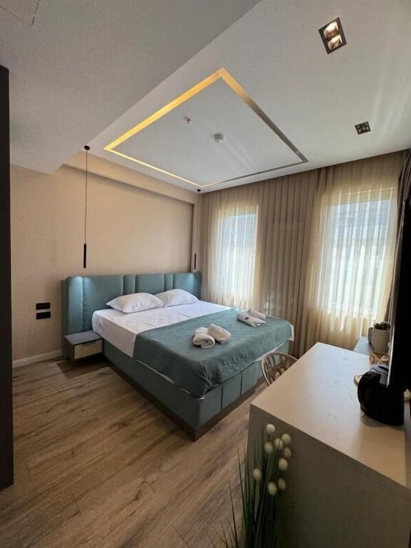 Une chambre moderne comprenant un lit, des tables de chevet, un bureau et un luminaire au plafond.