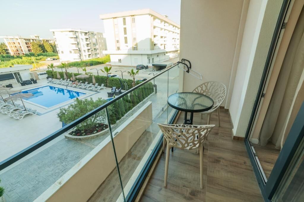 Un balcon avec une piscine, des chaises longues et une table.