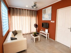 Ein Wohnzimmer mit Sofa, Couchtisch, Fernseher und einer Tür.