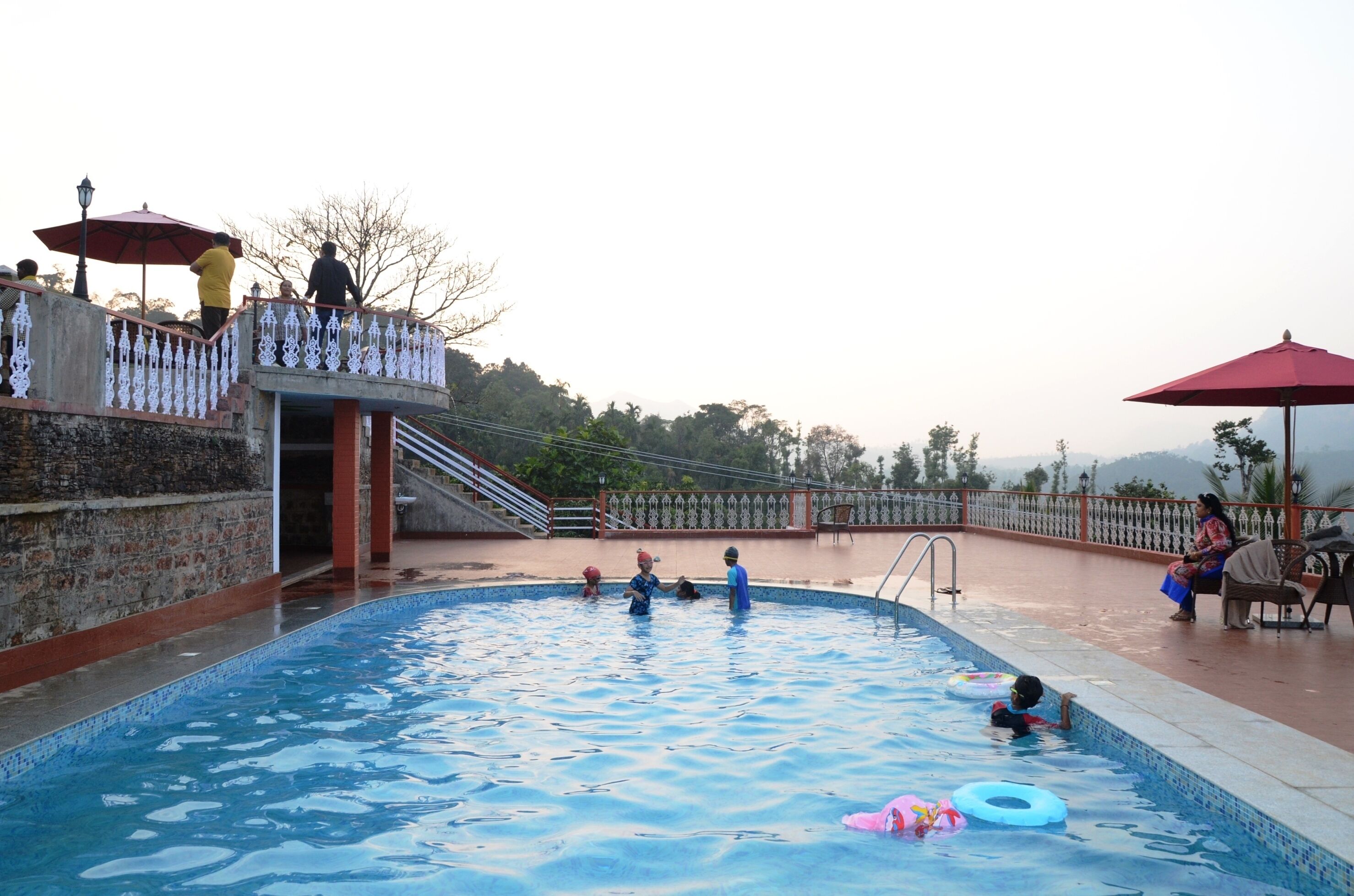 A swimming pool with people around it, a staircase, and a railing.