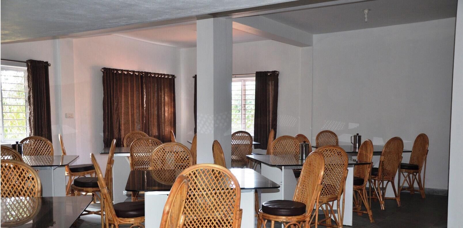 A conference room with tables and chairs, large windows with curtains, and a white ceiling.