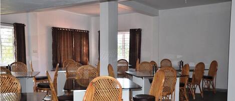 A conference room with tables and chairs, large windows with curtains, and a white ceiling.