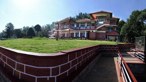 A large building with a flat roof, a swimming pool, and a grassy area. - Upasana Retreat (Mudigere)