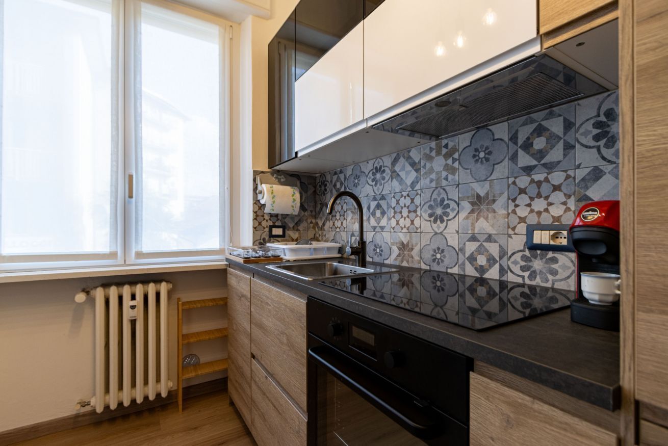 Eine moderne Küche mit Fenster, Heizkörper, Spüle und Kaffeemaschine.