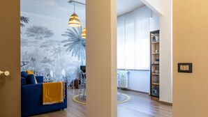 A living room with a blue sofa, a yellow throw blanket, and a wall mural. - Casa Giada - Downtown Arona - 500 m from the lake - WiFi - By Guestaly (Arona)