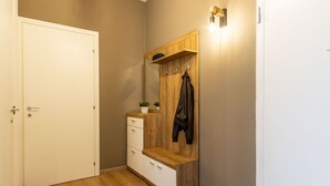 A hallway with a wooden bench, a coat rack, and a door. - Casa Giada - Downtown Arona - 500 m from the lake - WiFi - By Guestaly (Arona)