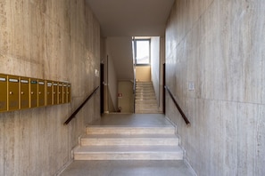 A staircase with marble walls, a metal handrail, and a fire extinguisher.