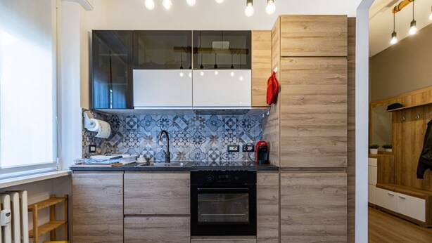 A modern kitchen with wooden cabinets, a built-in oven, and a patterned backsplash. - Casa Giada - Downtown Arona - 500 m from the lake - WiFi - By Guestaly (Arona)