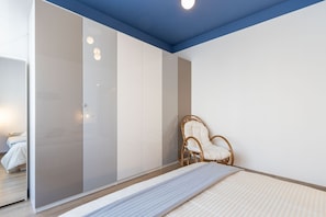 A bedroom with a bed, a wardrobe, a chair, and a mirror.