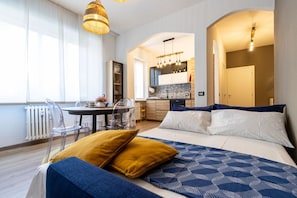 Ein modernes Hotelzimmer mit Bett, Esstisch und einer Küchenzeile.