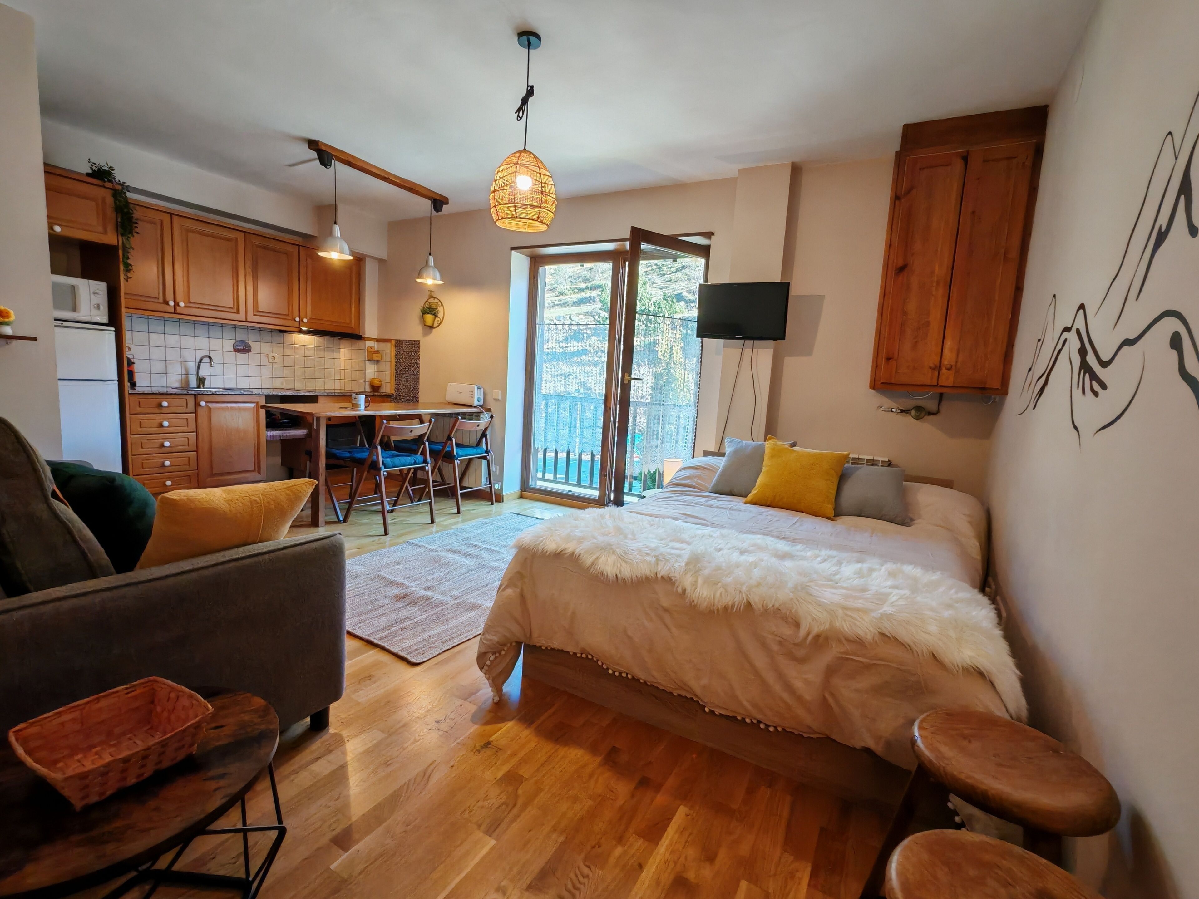 Une chambre avec un lit, un canapé, une table à manger avec des chaises, un coin cuisine et un balcon avec vue.