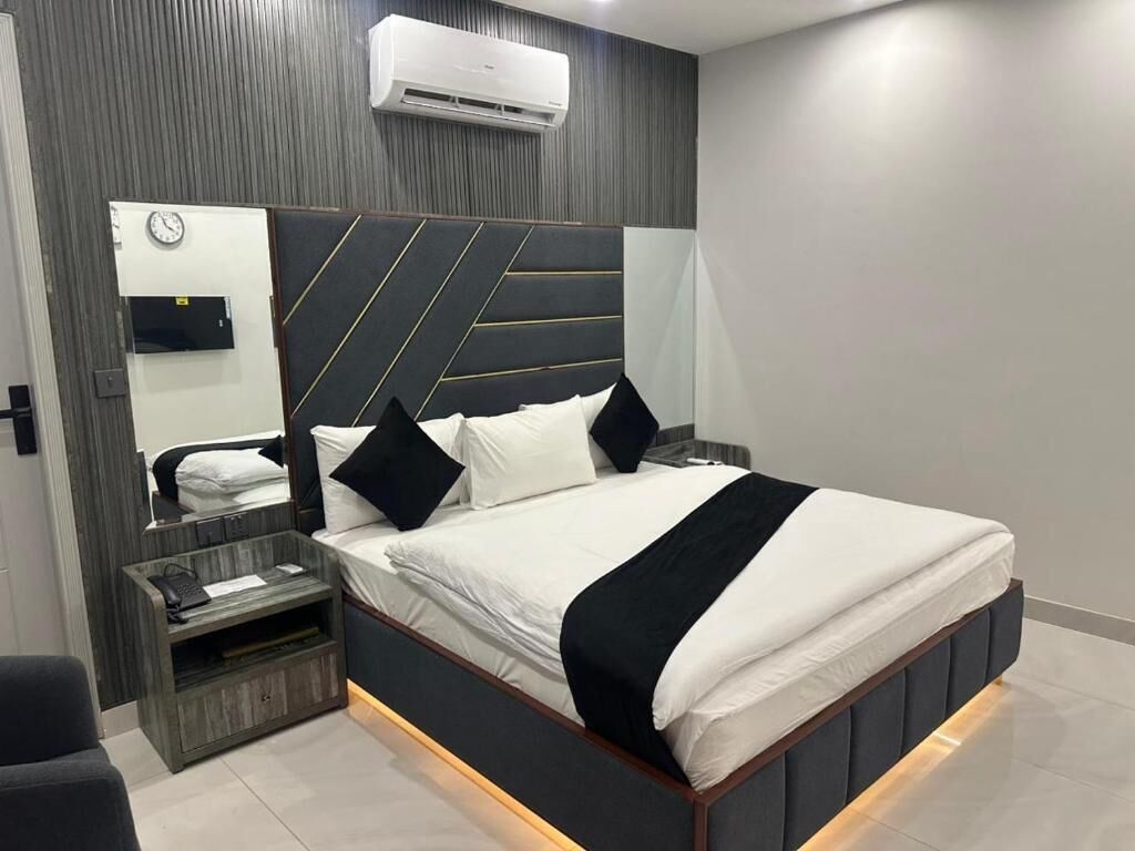 Een moderne slaapkamer met een bed, nachtkastjes, een klok en een airconditioning.