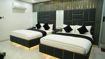 A modern bedroom with two beds, a mirrored headboard, and a built-in air conditioning unit.